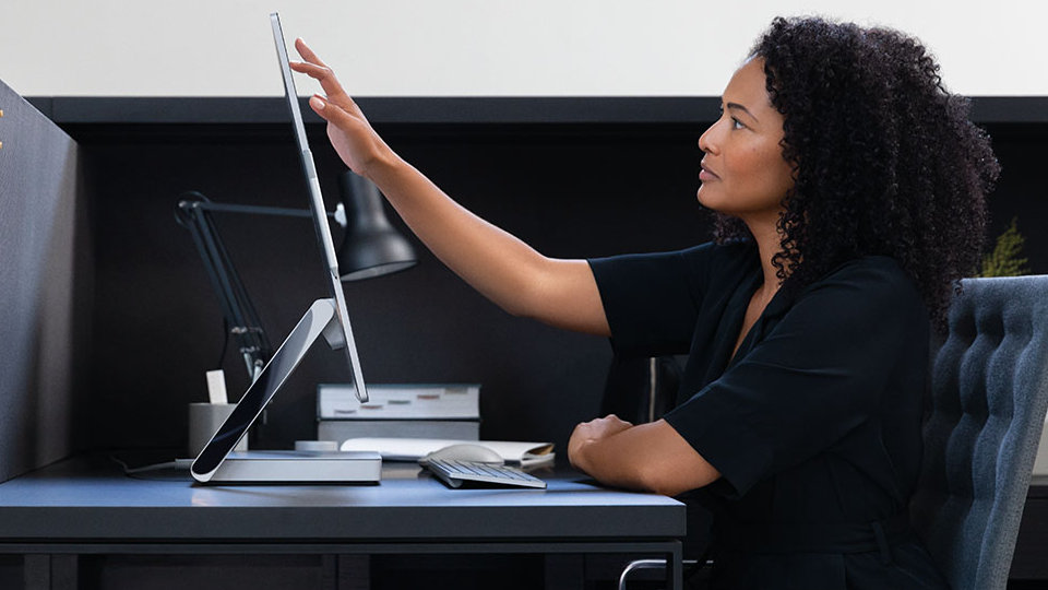 A person touches the display of Surface Studio 2 for Business.