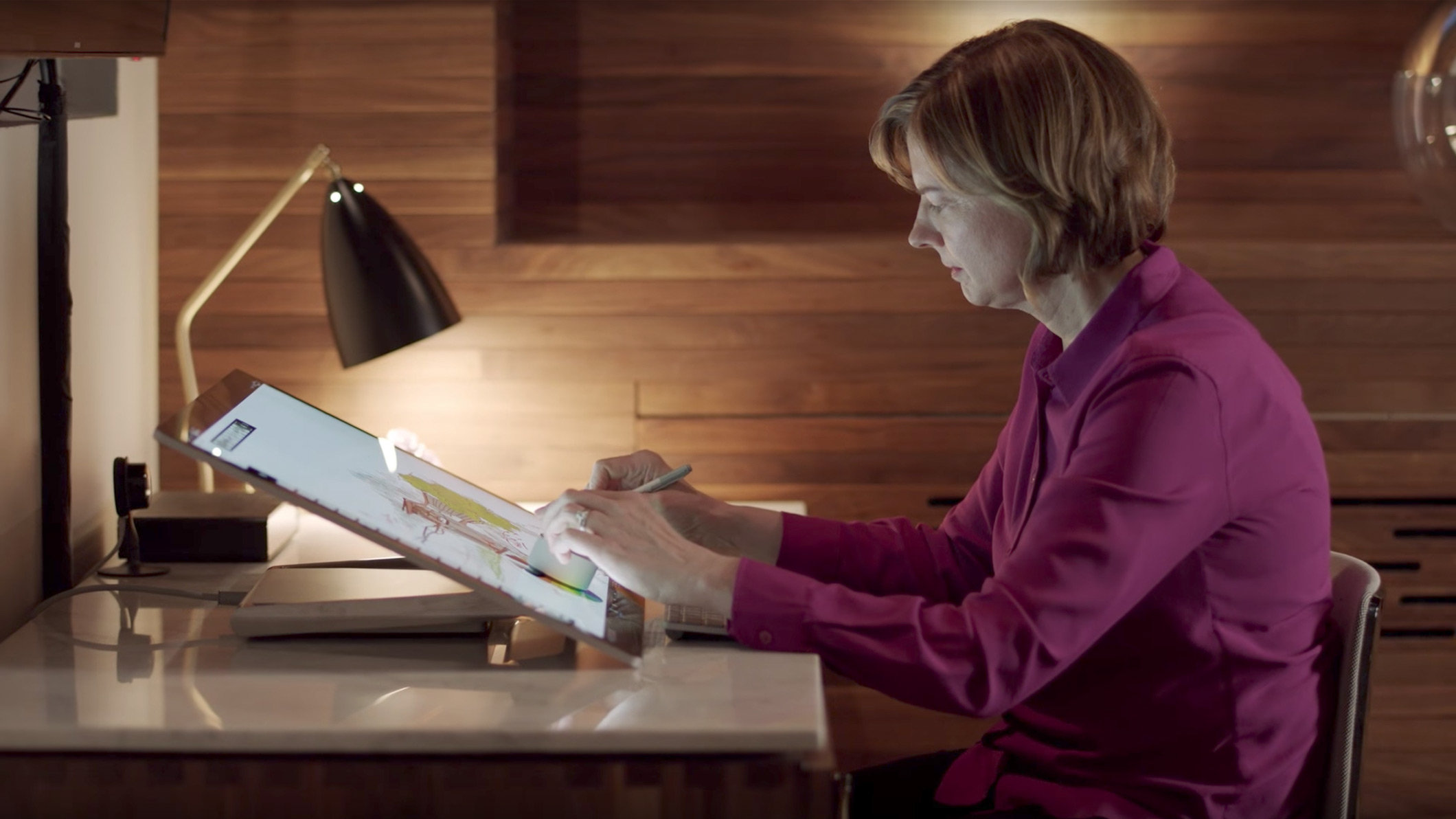 A woman uses Surface Dial on the screen of Surface Studio 2.