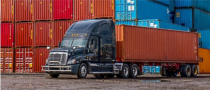 Een vrachtwagen met oplegger die geparkeerd staat voor containers.