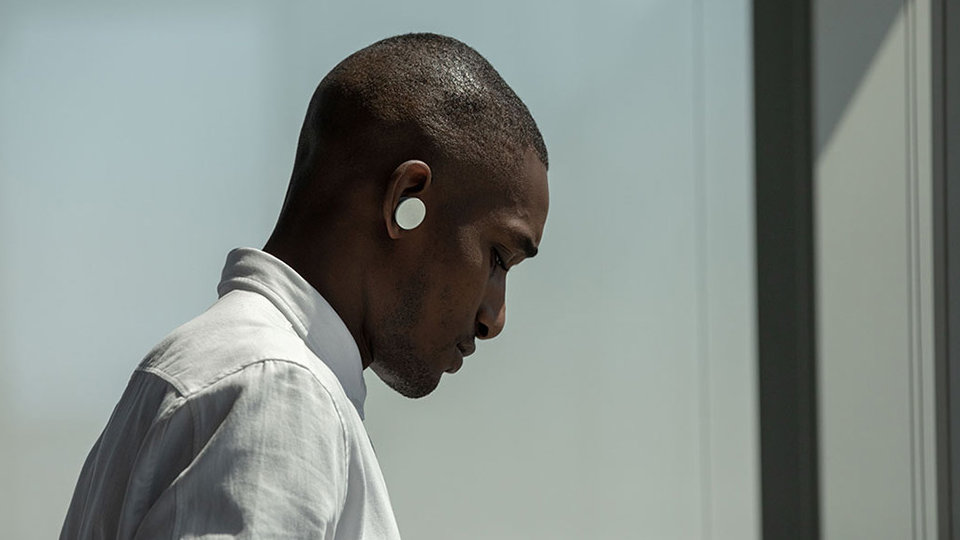 A man works on a Surface Hub 2 in PowerPoint while wearing Surface Earbuds.