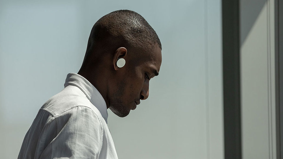 Mężczyzna ze słuchawkami dousznymi Surface Earbuds w uszach pracujący na urządzeniu Surface Hub 2 w programie PowerPoint