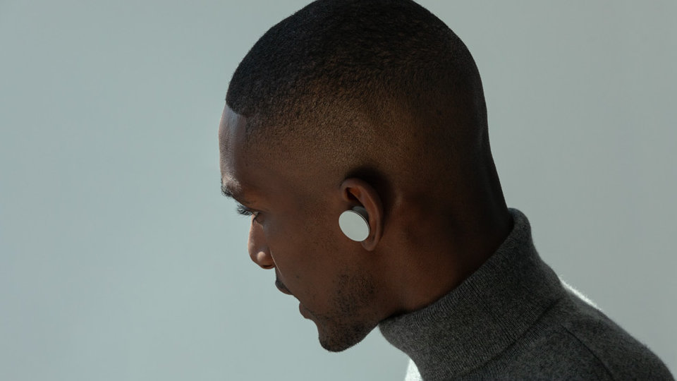 Ein Mann trägt Surface Earbuds, während er auf einen Anruf antwortet.