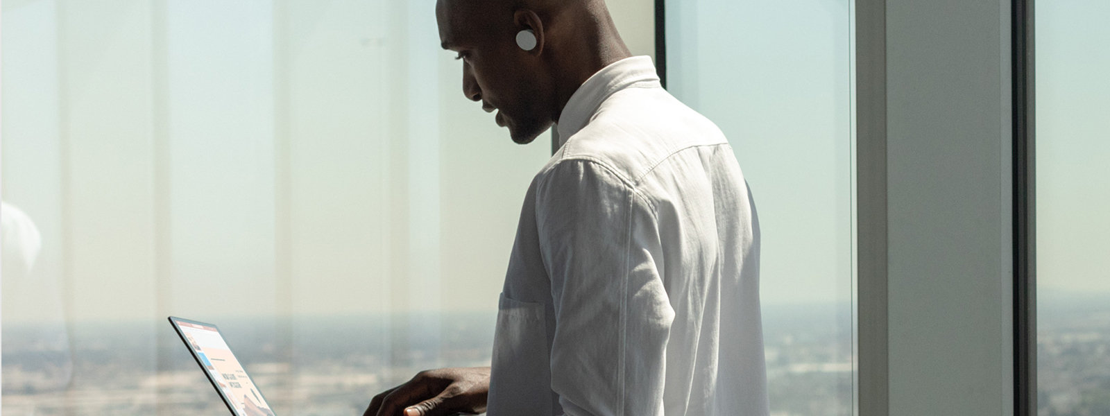 Osoba korzysta z urządzenia Surface sparowanego z słuchawkami Surface Earbuds.