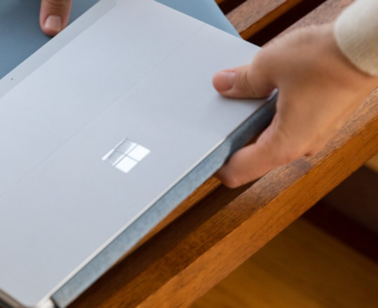 A woman picks up Ice Blue Sochi with a Surface Go 2.