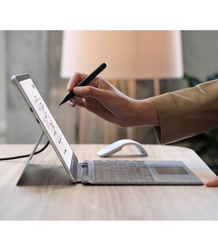 A person’s hand holding Surface Slim Pen 2 for Business in front of a Surface device screen.