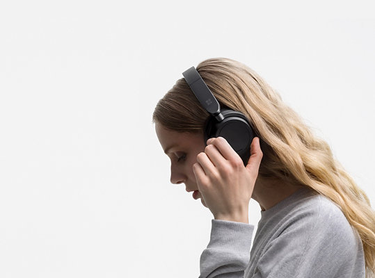 A woman wears her Surface Headphones 2.