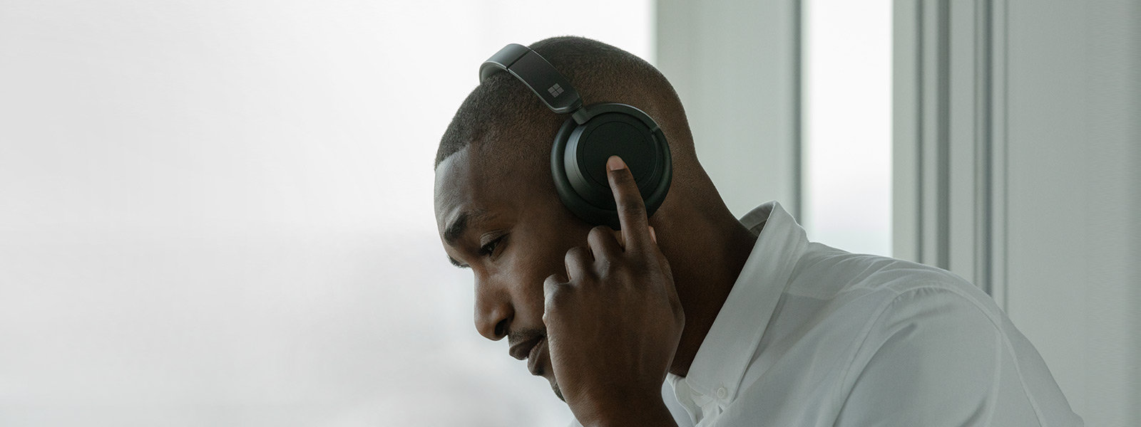 Ein Mann trägt schwarze Headphones 2, während er das linke Bedienelement berührt