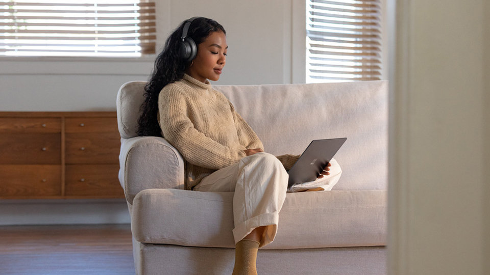 Een vrouw draagt Headphones 2 terwijl ze een programma op een Surface-computer bekijkt