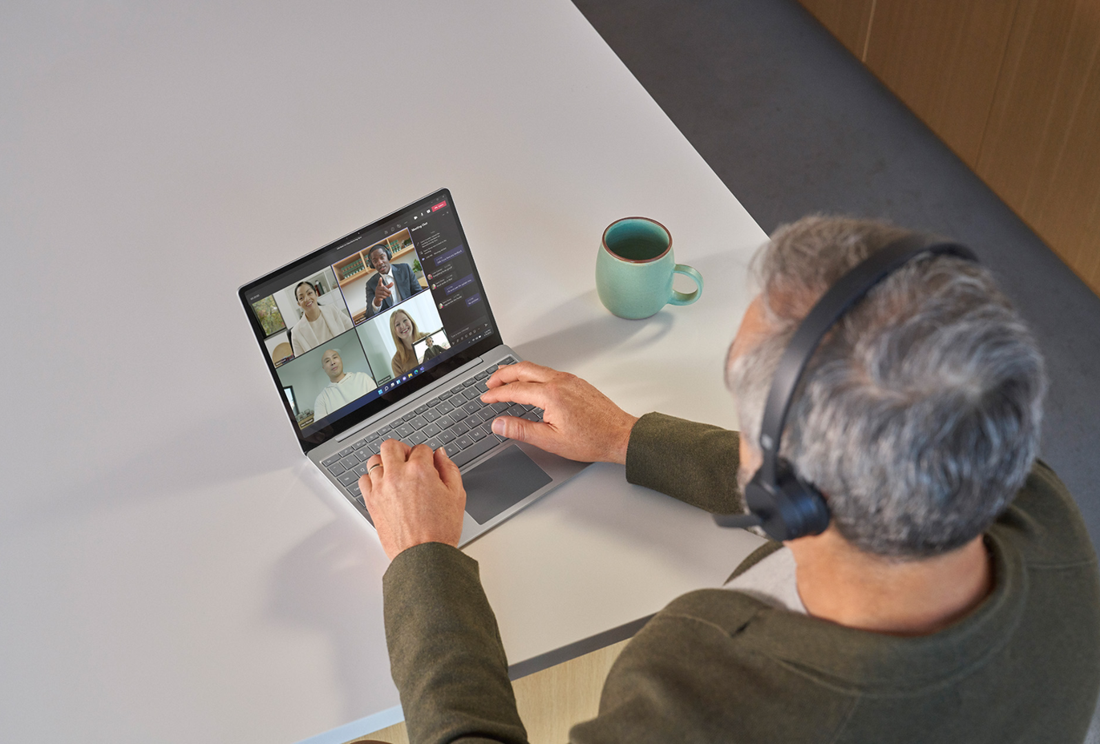 Felülnézeti kép egy Surface Headphones 2 fejhallgatót viselő személyről, aki egy Teams-megbeszélésen vesz részt Surface Laptop Go 3 eszközén.