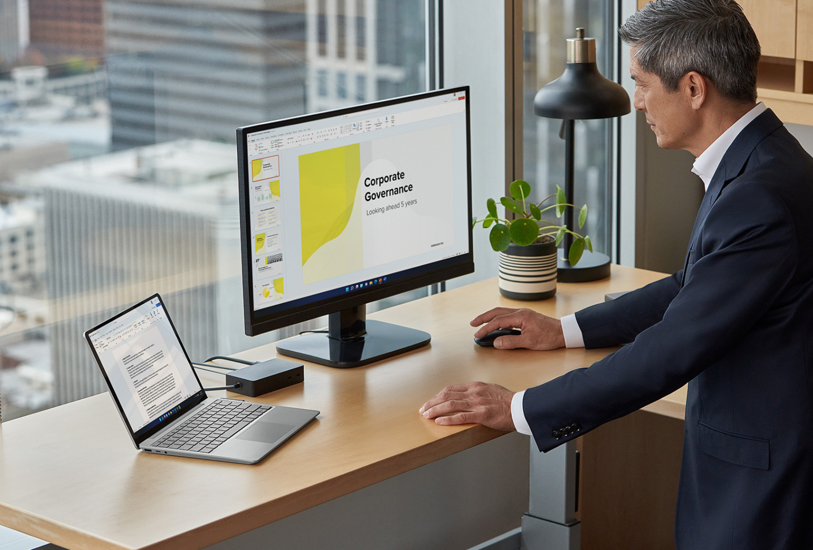 Um homem de pé no seu escritório em casa a interagir com um Surface Laptop Go 3