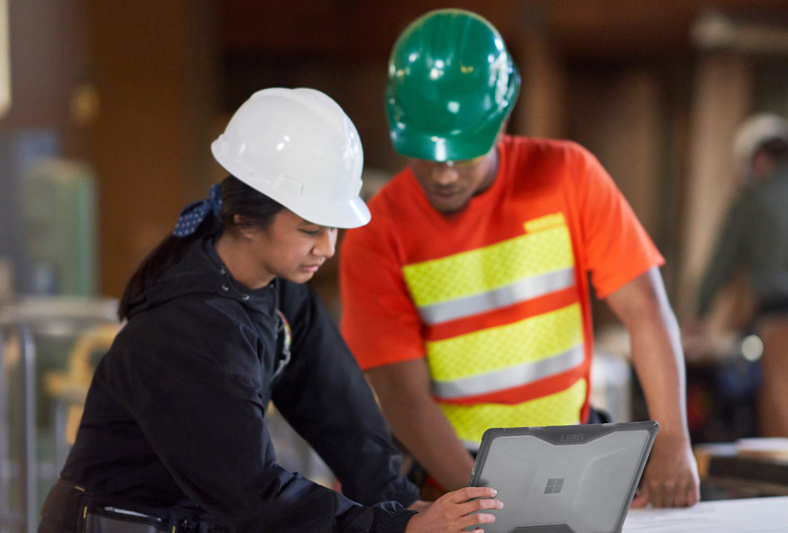 Two people in a manufacturing setting interact with the touchscreen on a Surface Laptop Go 3