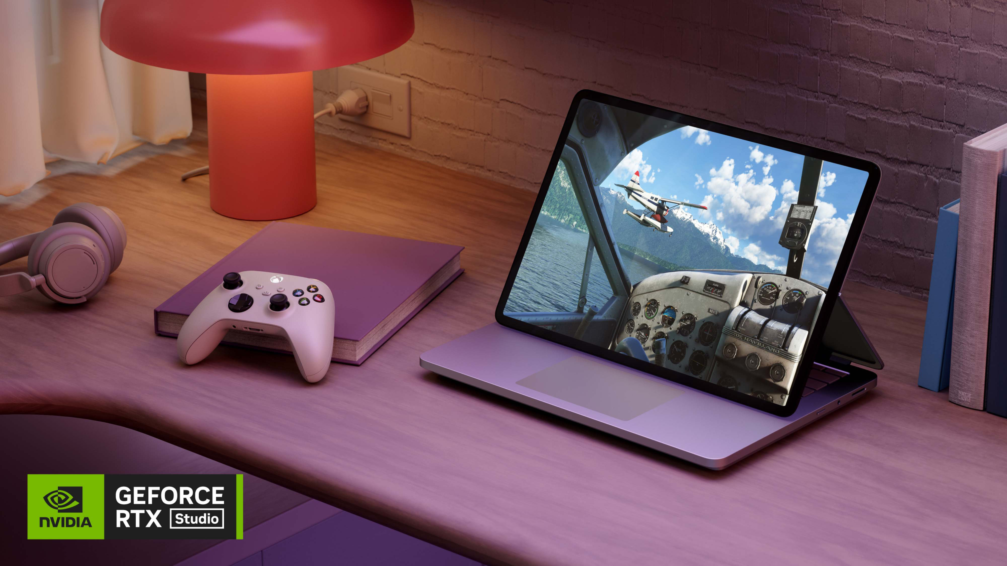 Surface Laptop Studio 2 in stage mode along side headphones, a game controller and a book on a wooden desk.