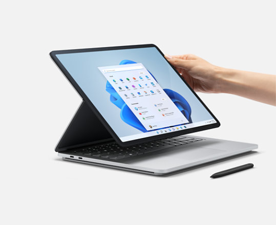 Die Hand einer Person hält ein Surface Laptop Studio mit einem Surface Pen.