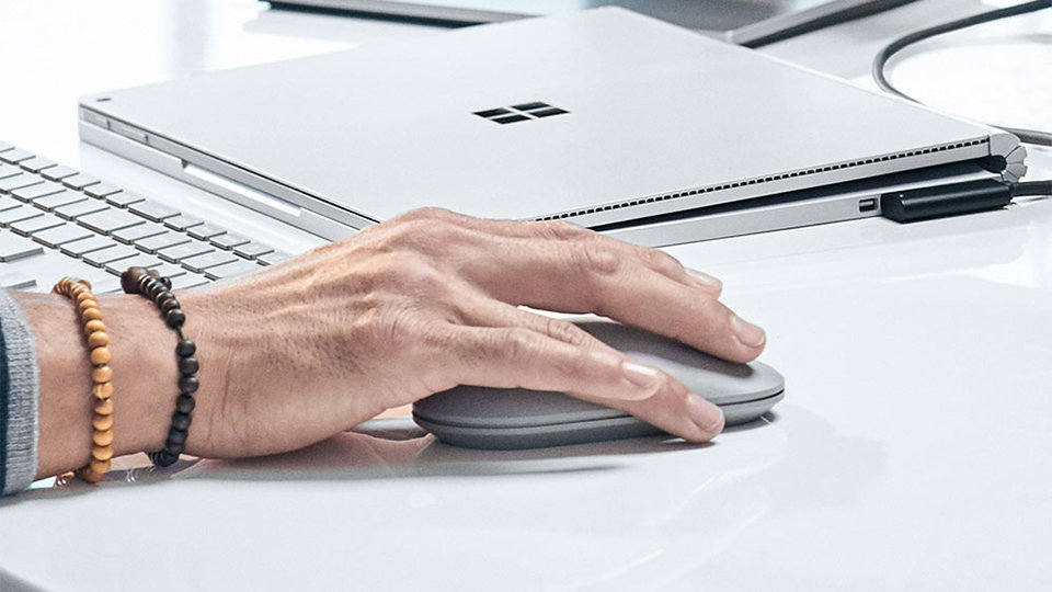 A person’s hand upon the Surface Mouse.