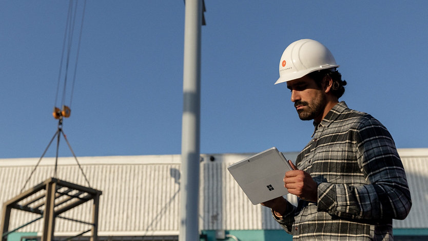 Person on a job site holding a Surface device.