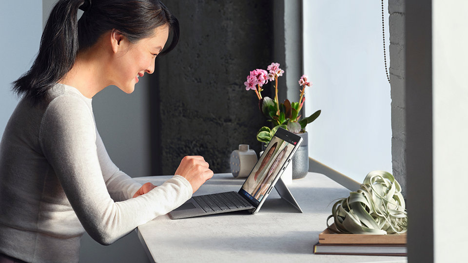 Een persoon zit aan een bureau en werkt met een Surface Pro 8 voor zakelijk gebruik.