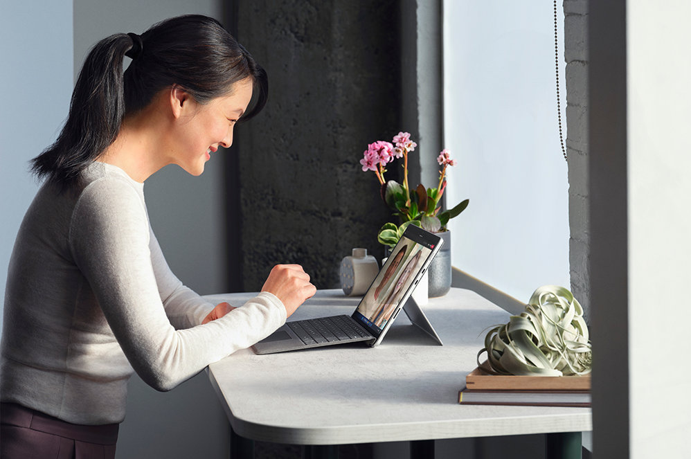Een persoon zit aan een bureau en werkt met een Surface Pro 8 voor zakelijk gebruik.
