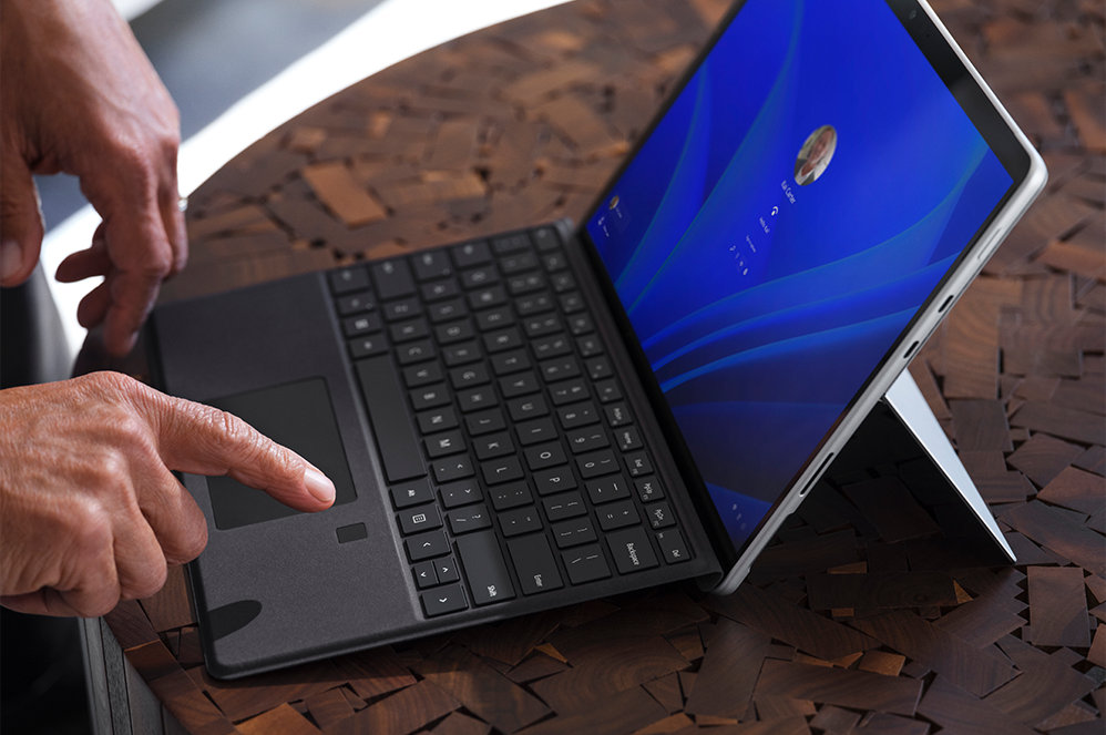 Een persoon zit aan een tafel in een vergaderzaal met een Surface Pro 8 voor zakelijk gebruik op de tafel.