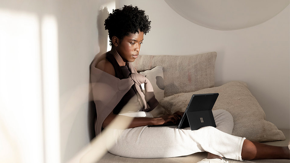 Une personne assise utilisant un appareil Surface Pro et un clavier Surface Pro Signature doté d’un lecteur d’empreintes digitales. 