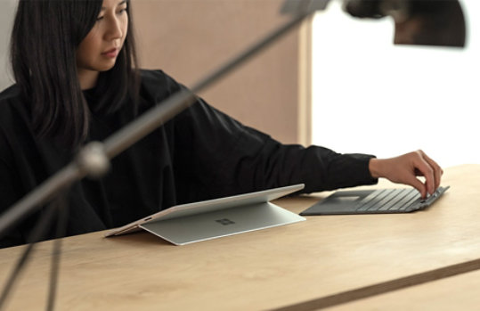 A woman using Surface Pro X in studio mode.