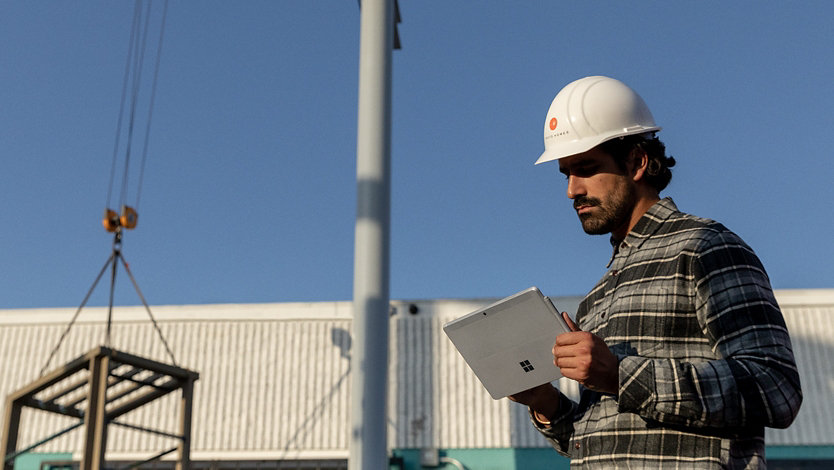 Een werknemer gebruikt een Surface-apparaat op een bouwterrein.