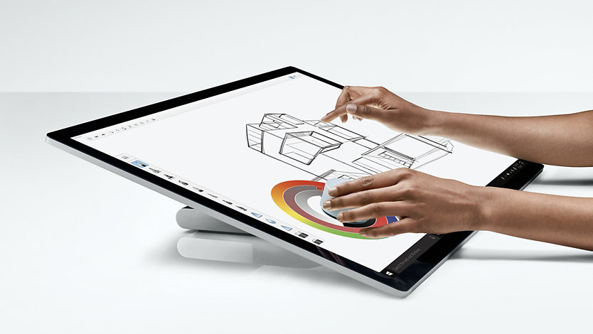 A person uses Surface Studio 2 at a drafting angle.
