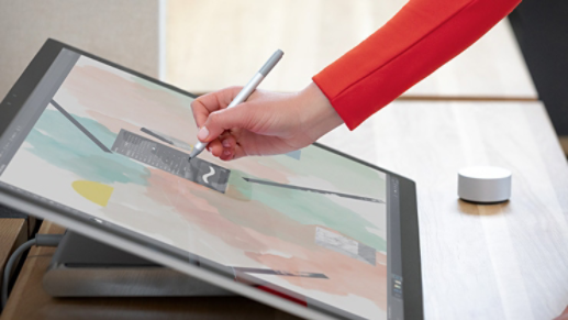  A person using a Surface Studio 2 with a Surface Pen and Surface Dial.