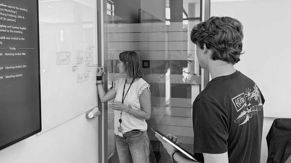 Two people discussing at a whiteboard in an office.