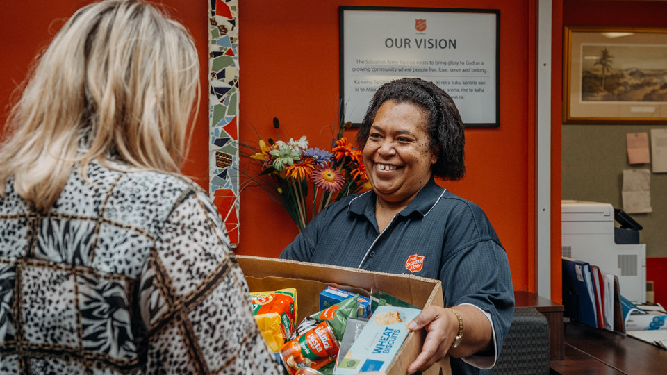 Two women exchanging a food box in a community center.