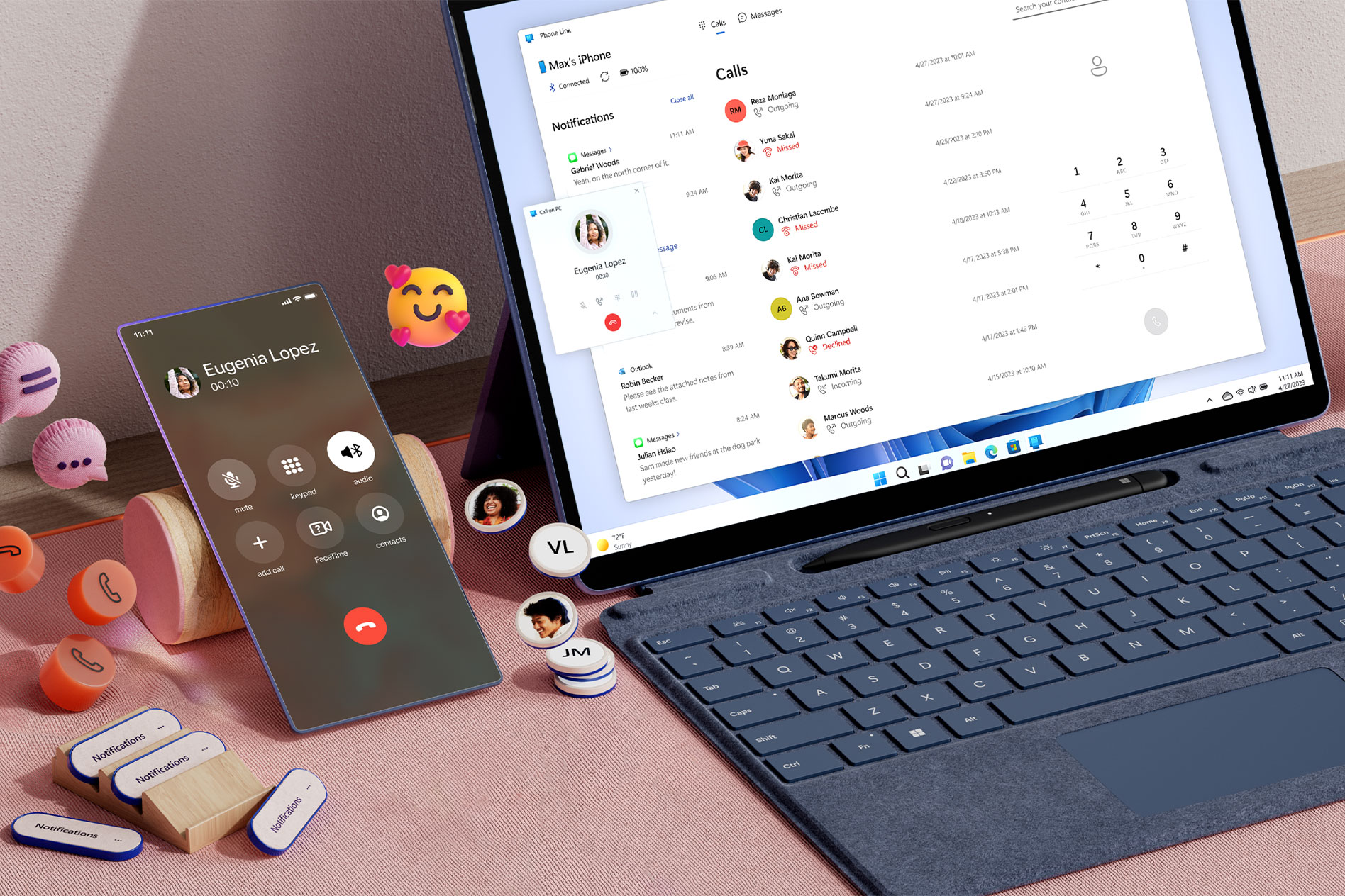 A Surface Pro 9 on a desk with phone call notifications on screen while a mobile phone rests next to the device with phone and chat icons and emojis floating around the phone.