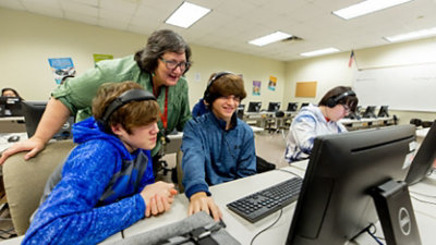 A teacher looking over students on computers.