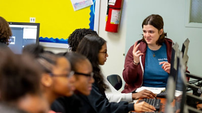 Female volunteer helps students in a computer lab.