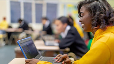 Student smiles while looking at her laptop.