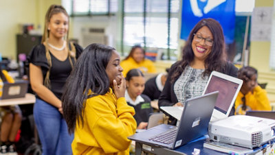 A teacher and volunteer instructor support a female student.