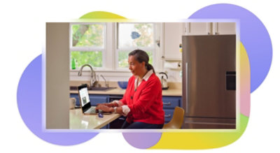 A person sitting at their kitchen counter using a laptop to participate in a Teams call.