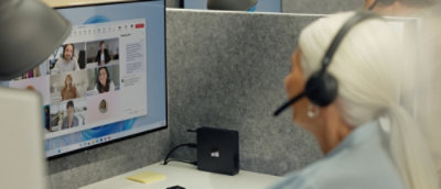 Person wearing a headset joins a video meeting on a desktop monitor.