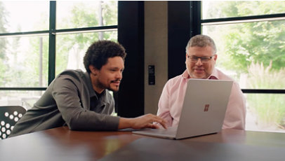 Microsoft Chief Questions Officer, Trevor Noah and TrueMedia.org Founder, Oren Etzioni look at a laptop screen.
