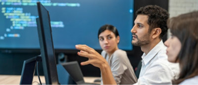 A man and two women looking at computer screen and discussing