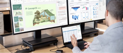 A man with two monitos and a laptop
