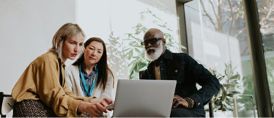 Three people looking at laptop screen