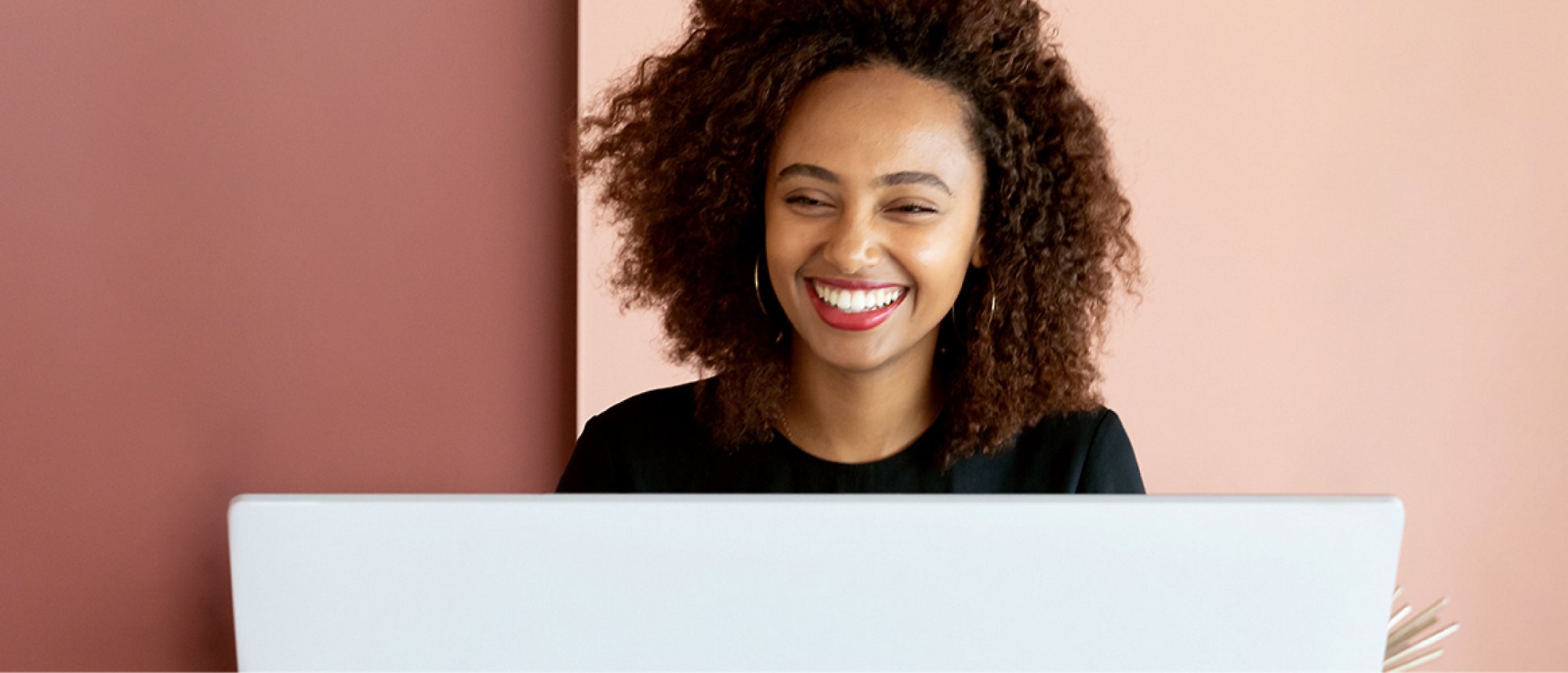 ผู้หญิงกำลังยิ้มและทำงานบนแล็ปท็อป