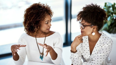 Two colleagues in a modern office discussing work together during a planning conversation.