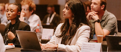 A group of people sitting at a table with laptops and papers.