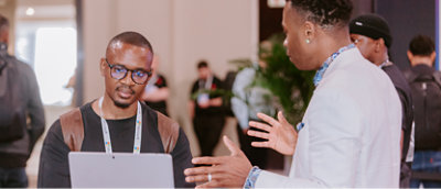 One man talking and other looking at a laptop.