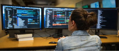 A woman sitting at a desk looking at a computer screen.