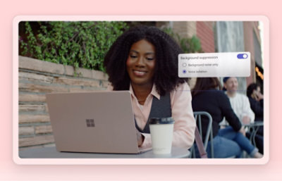 Woman working on a laptop at an outdoor café with a to-go coffee cup next to her. 