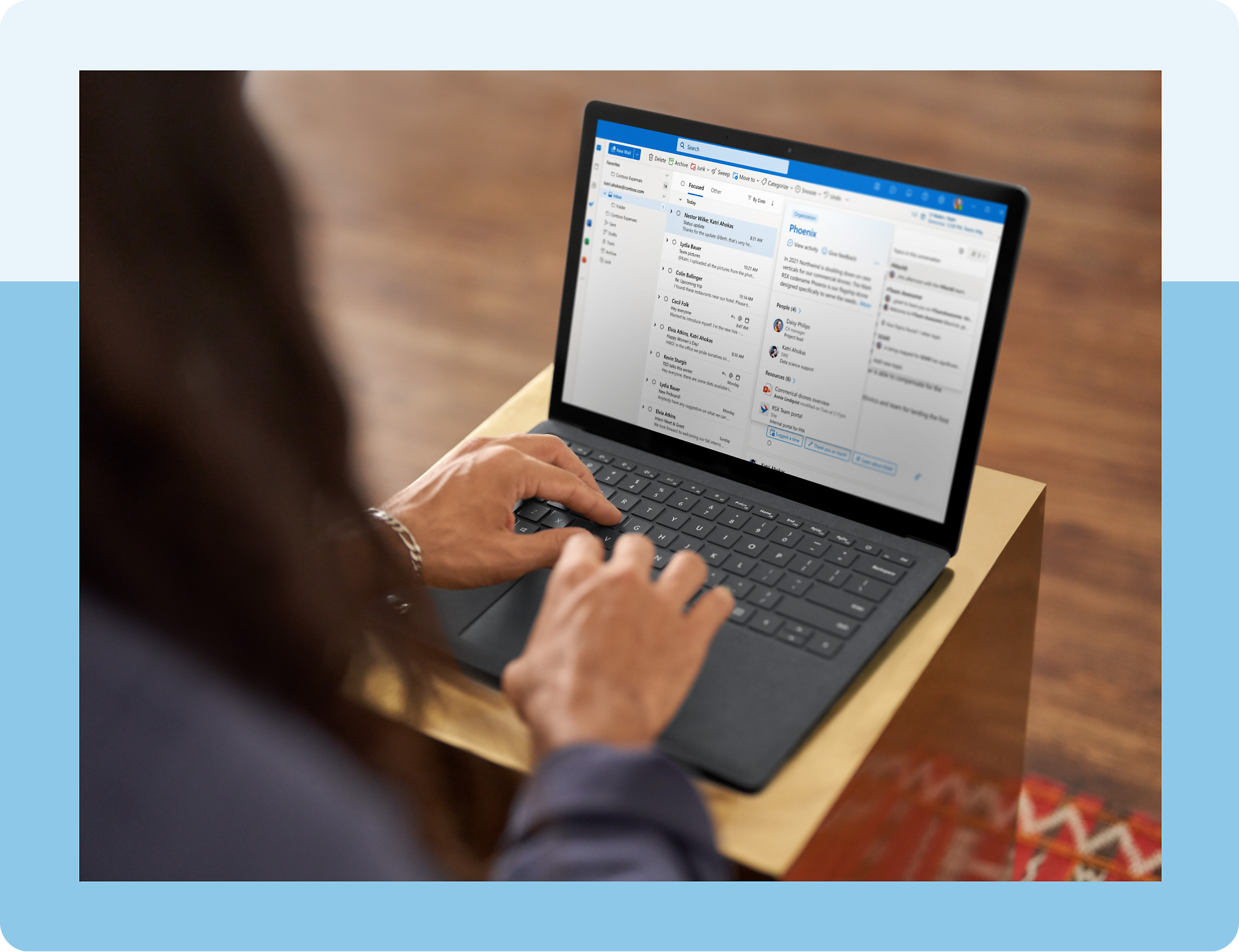 A person typing on a laptop computer displaying the Outlook app