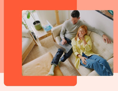 A man working on his laptop sitting in the sofa and woman lies on the sofa with her head on the shoulder of the man