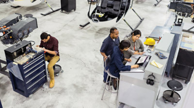 Eine Person in einem Lagerhaus, die ein Maschinenteil hält