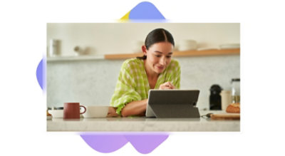 Una persona seduta a un'isola della cucina mentre usa un tablet e una penna.